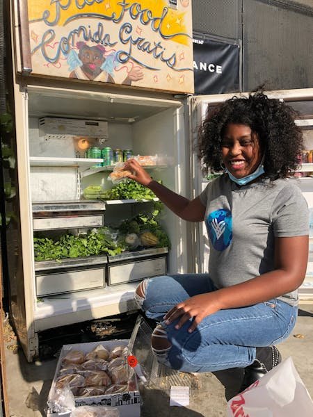 A black female activist looking at camera next to a food bank 